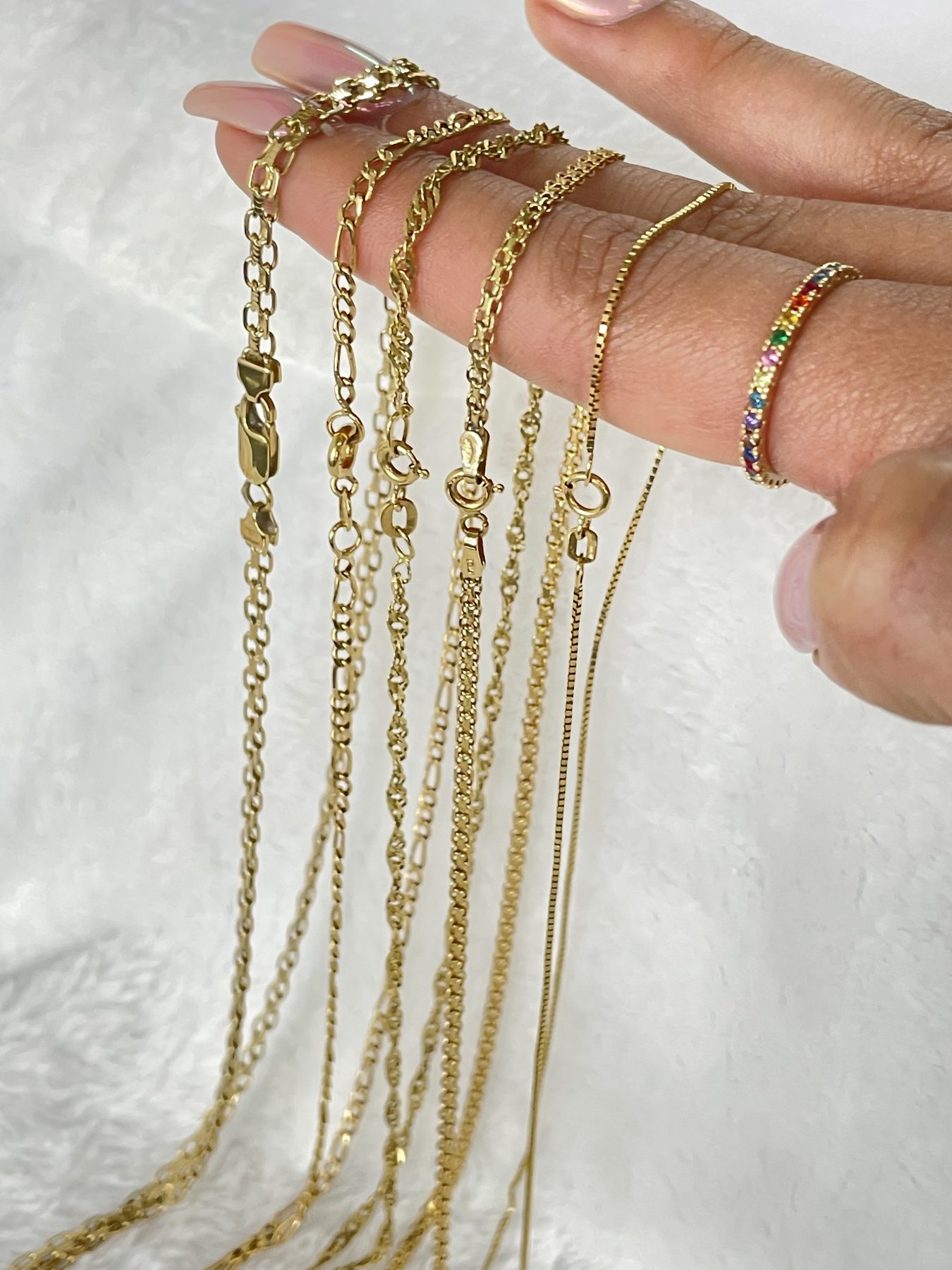 Cadenas finas de oro exhibidas sobre los dedos