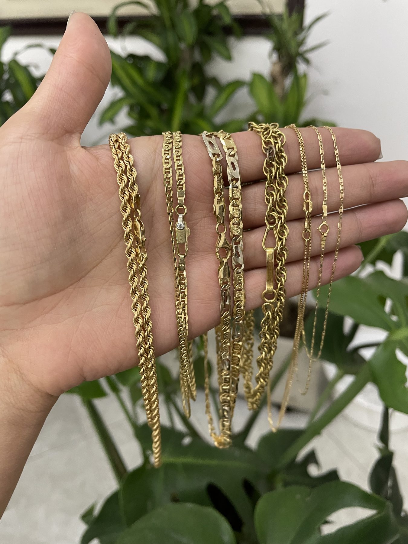 Cadenas de oro variadas exhibidas en la mano