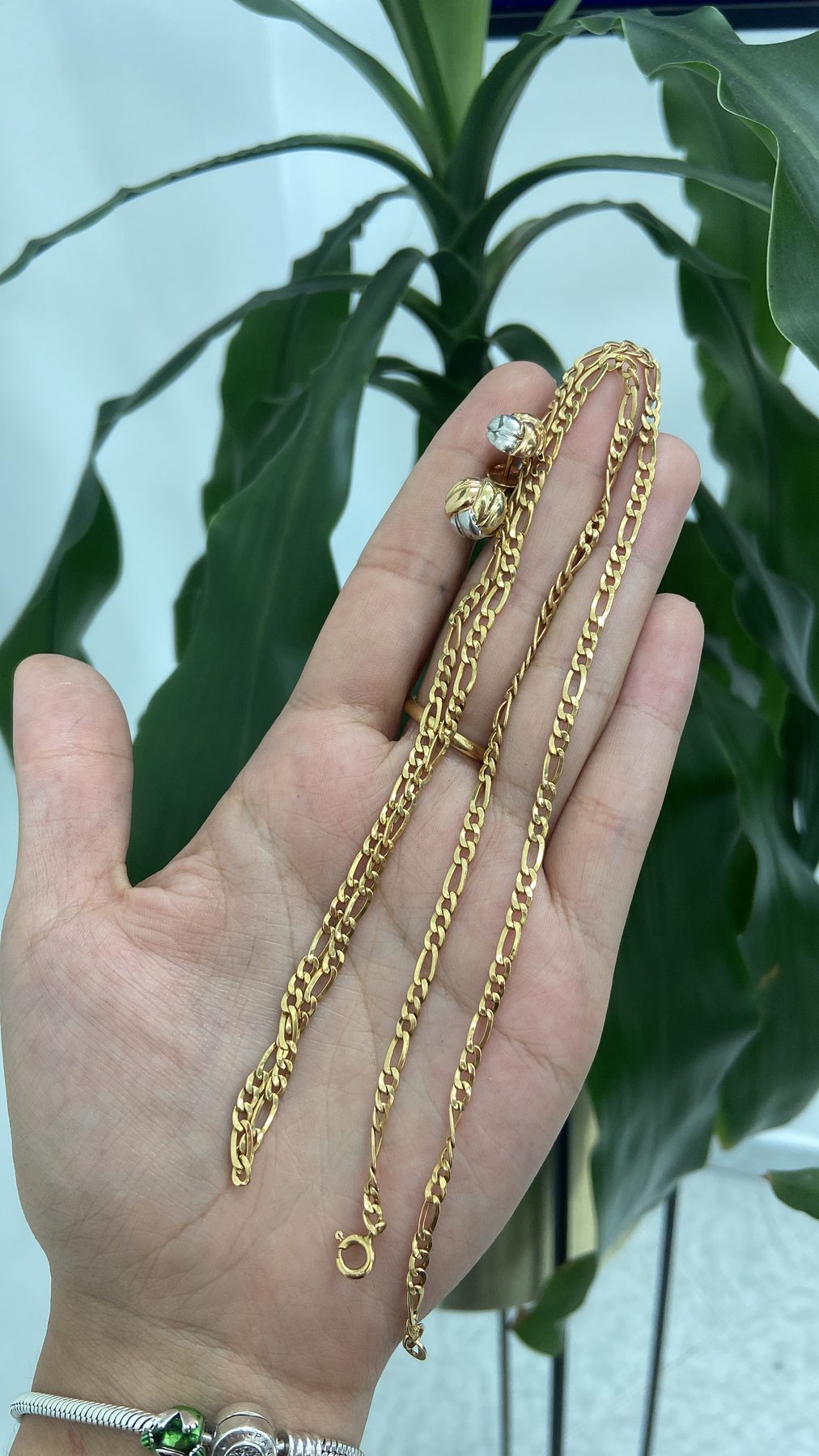Cadena y aretes de oro sostenidos en la mano